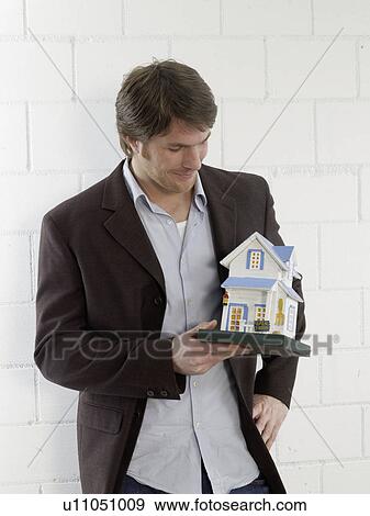 Stock Photo - Mann holding a small model house. Fotosearch