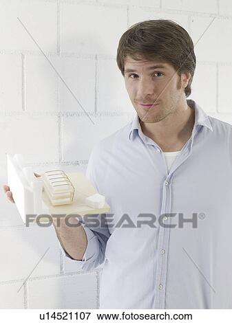 Stock Photo - Mann holding a small model house. Fotosearch