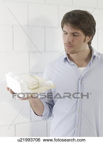 Stock Photograph - Mann holding a small model house. Fotosearch