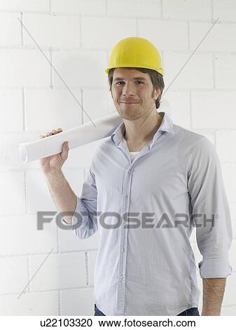 Stock Image - Mann waering a helmet with a paper roll. Fotosearch