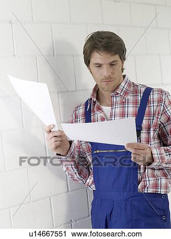 Mann wearing work wear holding contruction plans View Large Photo Image Stock Image - Mann wearing work wear holding contruction plans. Fotosearch