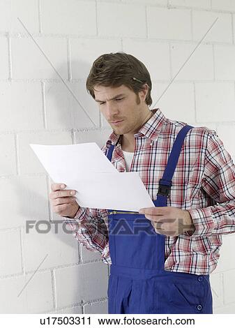 Mann wearing work wear holding contruction plans View Large Photo Image Stock Image - Mann wearing work wear holding contruction plans. Fotosearch