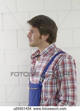 Mann wearing work wear with a pencil behind his ear View Large Photo Image Picture - Mann wearing work wear with a pencil behind his ear. Fotosearch