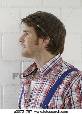 Mann wearing work wear with a pencil behind his ear View Large Photo Image Stock Photo - Mann wearing work wear with a pencil behind his ear. Fotosearch
