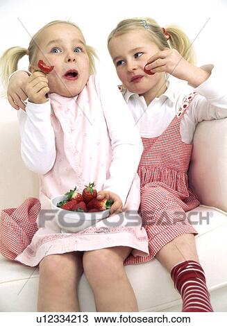 Two girls enjoying strawberries View Large Photo Image Stock Image - Two girls enjoying strawberries. Fotosearch
