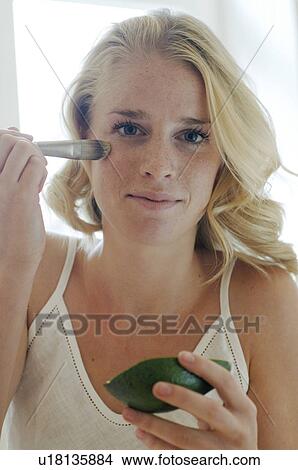 Picture - Blonde woman applying avocado mask. Fotosearch