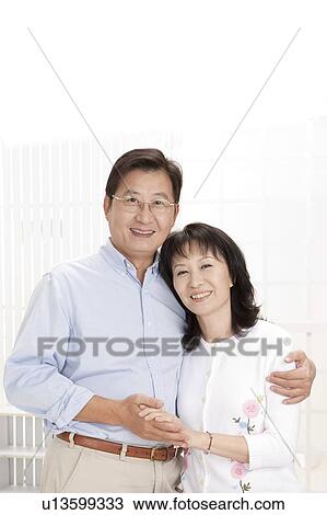 Stock Image - Couple, Couple bonding together, holding hands and looking at the camera with smile. Fotosearch