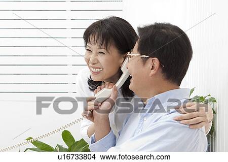 Picture - Couple, Couple holding telephone together and smiling happily. Fotosearch