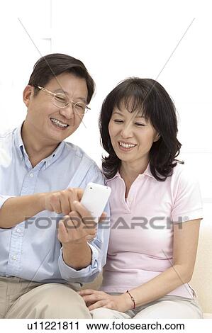 Stock Image - Couple, Couple looking at the mobile phone together and smiling happily. Fotosearch