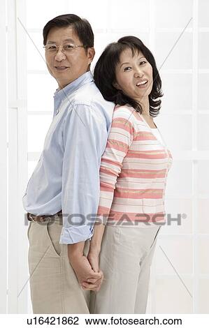 Couple, Couple standing of back to back and smiling at the camera View Large Photo Image Stock Image - Couple, Couple standing of back to back and smiling at the camera. Fotosearch