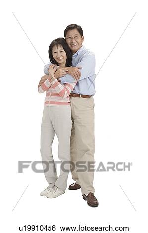Stock Photograph - Couple, Couple standing with arms around and smiling at the camera. Fotosearch