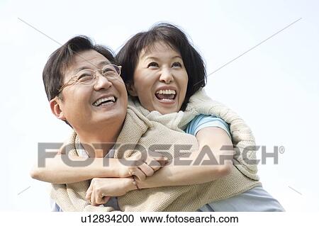 Stock Image - Couple, Wife bonding husband with arms around and smiling happily. Fotosearch