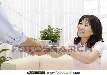 Stock Photography - Couple, Wife getting a cup of tea from husband and smiling. Fotosearch