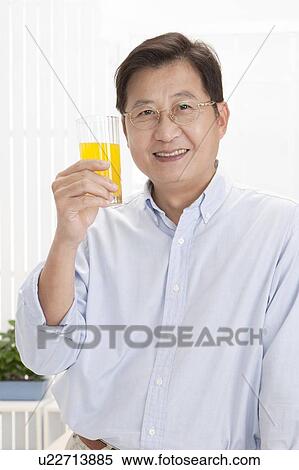Stock Photography - Husband, Man holding a glass of juice and smiling at the camera. Fotosearch