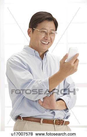 Stock Photo - Husband, Man holding mobile phone and smiling. Fotosearch