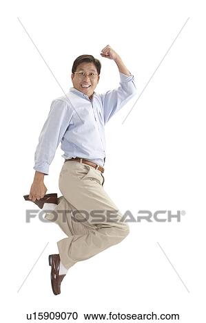 Stock Image - Husband, Man jumping in mid-air with arms raised and smiling. Fotosearch