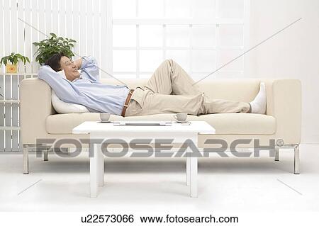 Stock Photograph - Husband, Man lying on sofa and smiling. Fotosearch