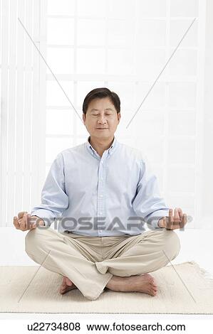 Stock Photo - Husband, Man making lotus position with eyes closed. Fotosearch