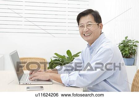 Stock Photograph - Husband, Man using laptop and smiling at the camera. Fotosearch