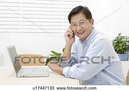 Stock Image - Husband, Man using mobile phone and smiling at the camera. Fotosearch