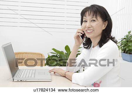 Picture - Wife, Woman holding mobile phone and smiling at the camera. Fotosearch