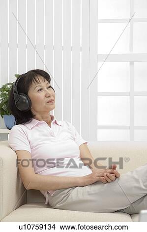 Picture - Wife, Woman lying on sofa and listening music with smile. Fotosearch