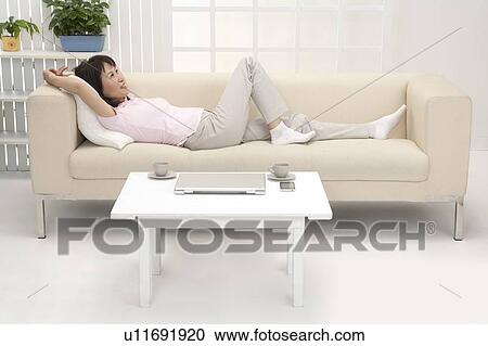 Stock Image - Wife, Woman lying on sofa and looking up with smile. Fotosearch
