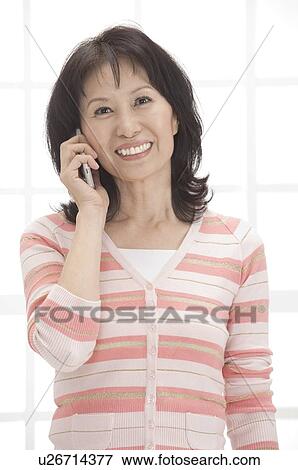 Woman holding mobile phone and smiling at the camera View Large Photo Image Stock Photo - Woman holding mobile phone and smiling at the camera. Fotosearch