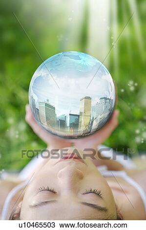 Stock Image - Lohas, Environmental Conservation, Digitally generated image of woman hands holding a sphere with buildings in it. Fotosearch