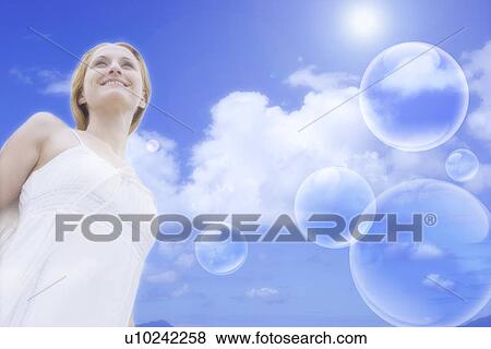 Stock Photo - Lohas, Environmental Conservation, Digitally generated image of a young woman and bubbles in the blue sky. Fotosearch