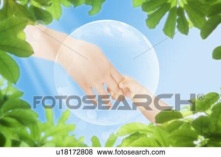 Stock Photo - Lohas, Environmental Conservation, Digitally generated image of human hand of an adult holding baby's hand, with green leaf in background. Fotosearch