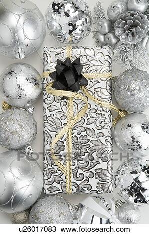 Stock Image - Christmas baubles around a packed gift with ribbon. Fotosearch