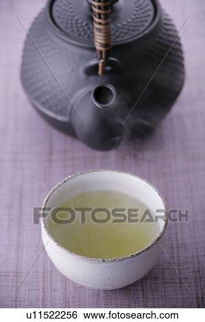 Stock Photograph - A cup of green tea and teapot. Fotosearch