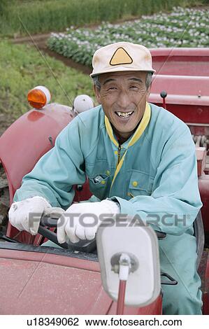 Stock Image - A farmer sitting in a tractor. Fotosearch