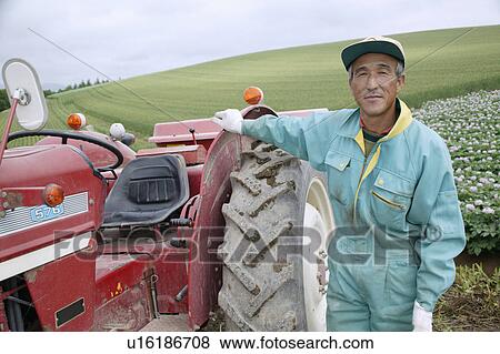 A farmer standing by tractor View Large Photo Image Stock Photo - A farmer standing by tractor. Fotosearch