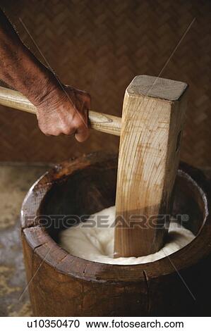 Stock Image - A man kneading rice cake with pestle. Fotosearch
