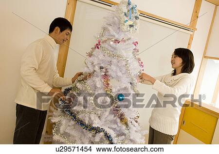 Picture - Couple decorating Christmas tree. Fotosearch