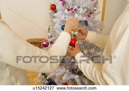 Stock Photo - Couple decorating Christmas tree. Fotosearch