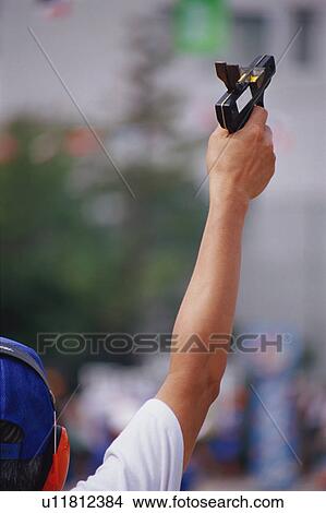 Man holding starting gun at school sports day View Large Photo Image Picture - Man holding starting gun at school sports day. Fotosearch