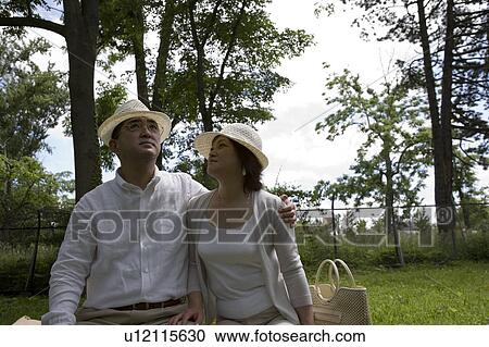 Stock Image - Mature couple sitting on bench. Fotosearch