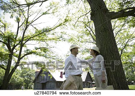 Mature couple standing by tree View Large Photo Image Picture - Mature couple standing by tree. Fotosearch