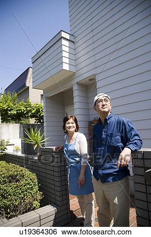 Mature couple standing in front of their house View Large Photo Image Stock Photograph - Mature couple standing in front of their house. Fotosearch