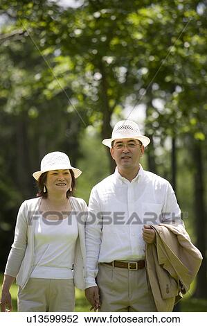 Stock Image - Mature couple walking in park. Fotosearch