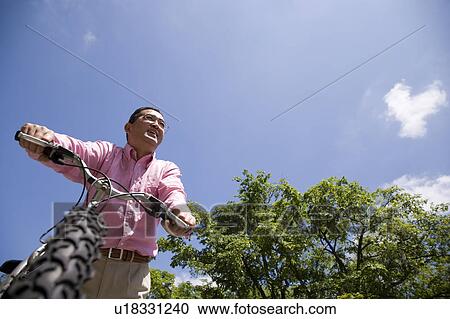 Stock Image - Mature man pushing mountain bike. Fotosearch