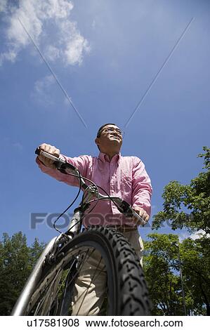 Stock Photo - Mature man pushing mountain bike. Fotosearch