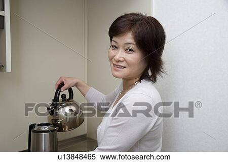 Mature woman pouring hot water into jug View Large Photo Image Stock Photography - Mature woman pouring hot water into jug. Fotosearch