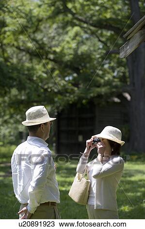 Stock Image - Mature woman taking photo of her husband. Fotosearch
