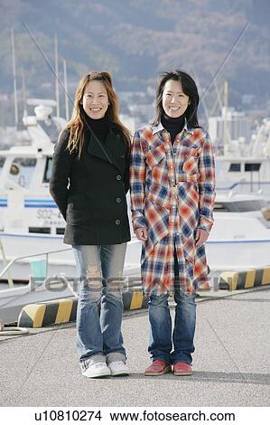 Picture - Portrait of young women standing at harbor. Fotosearch