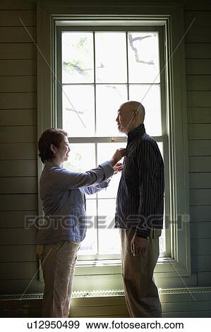 Stock Photo - Senior woman adjusting her husband's shirt. Fotosearch