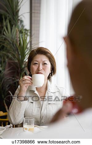 Stock Photograph - Senior woman drinking coffee, senior man in foreground. Fotosearch